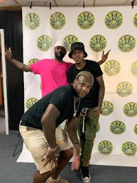 three men posing for a photo in front of a green background